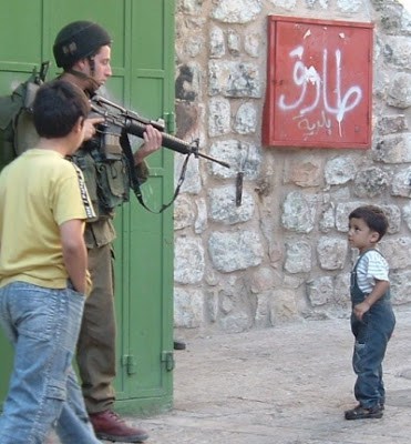 Israeli soldier pointing his weapon at a Palestinian child. Pic via  eagle of brass stacks